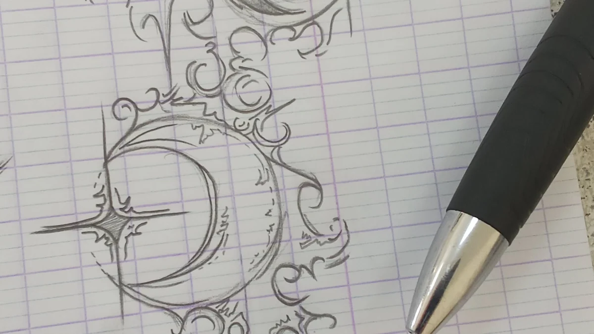 A detailed pen sketch of crescent moons and intricate swirling patterns on grid paper.