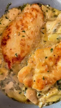Chicken piccata with artichoke hearts and green leafy vegetables in a creamy lemon caper sauce inside a Tuscan olive.