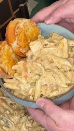 Creamy slow cooker chicken pot pie pasta with shredded chicken, peas, and carrots in a light blue textured bowl garnished.
