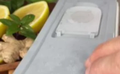 Hand opening a container with a yellowish mixture containing lemon and ginger.