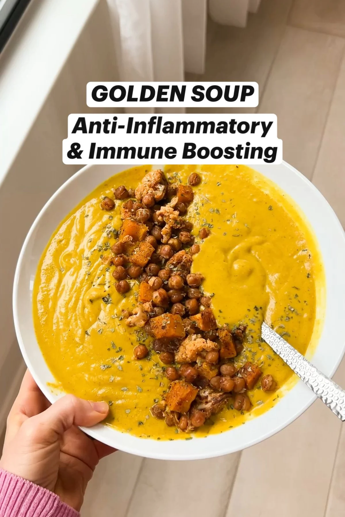 A bowl of golden soup, garnished with fresh herbs.