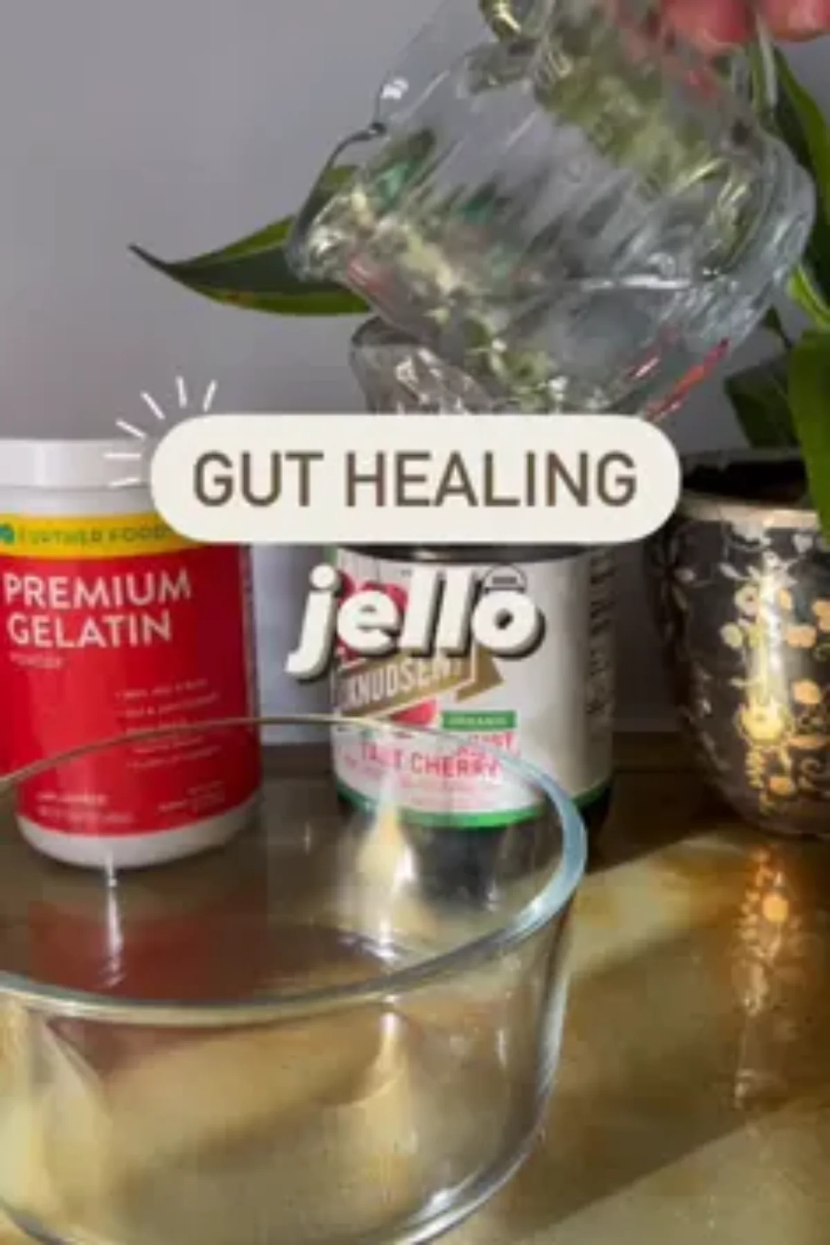 A clear glass bowl set on a light counter, filled with a pale golden gelatin that has just begun to set, surrounded by simple.