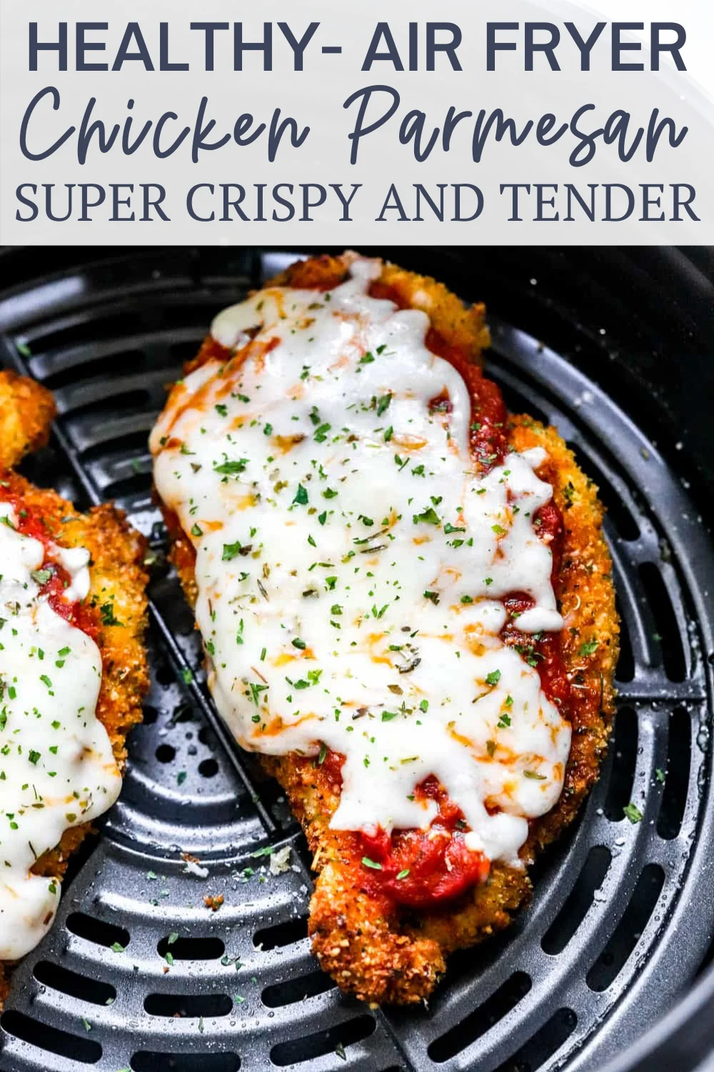 Two golden-crispy air-fried chicken breasts topped with red sauce, melted mozzarella, and parsley in a black air fryer.