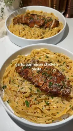 Two bowls of creamy garlic parmesan chicken pasta with golden chicken pieces and parsley garnish on a light countertop