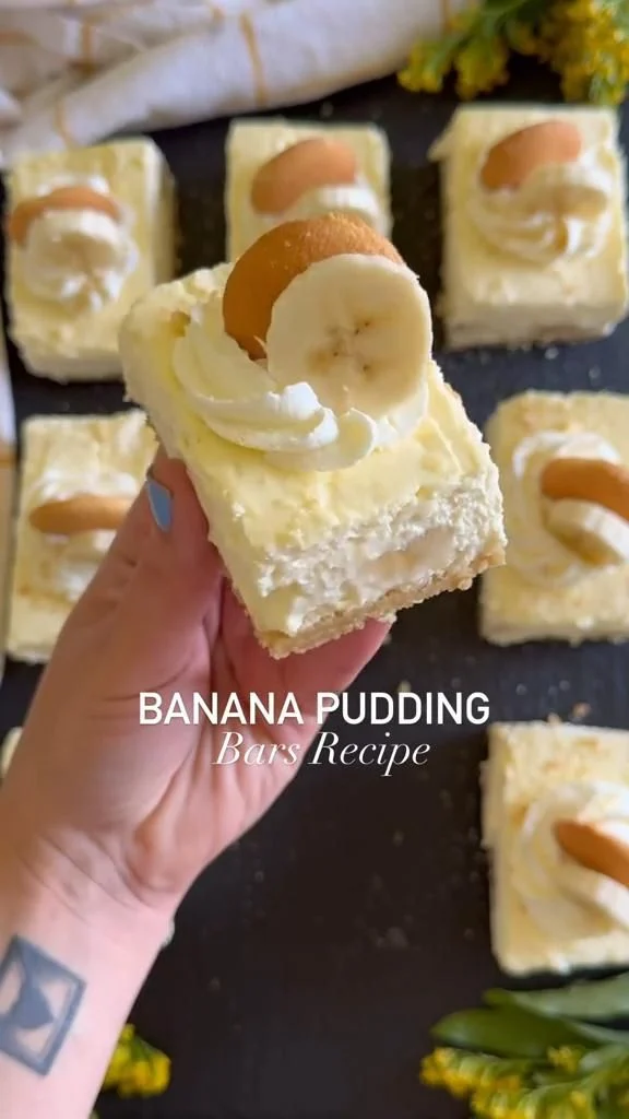 A rectangular serving of layered banana pudding bars with whipped topping, a sliced banana, and toasted almond on top.