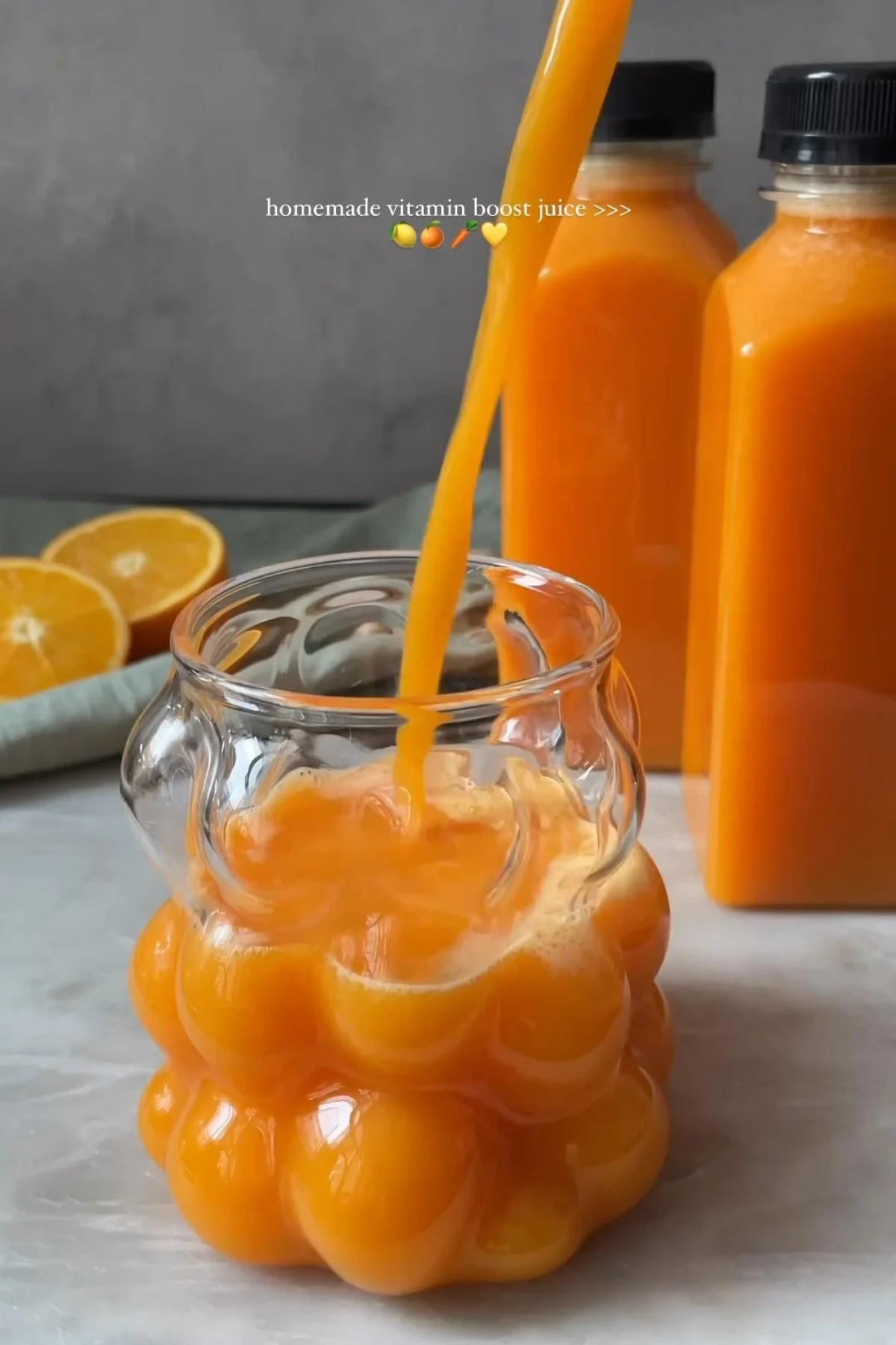 A close-up shot of a glass of bright orange juice with visible pulp, garnished with an orange slice.