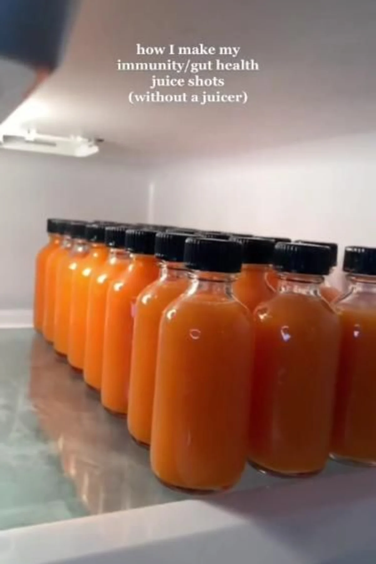 A colorful glass of fresh juice shot surrounded by whole fruits and vegetables on a kitchen counter.