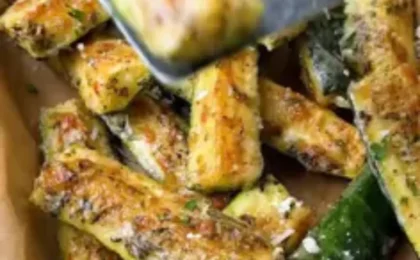 Crispy keto zucchini fries served with a small dish of dipping sauce on a light wood surface.