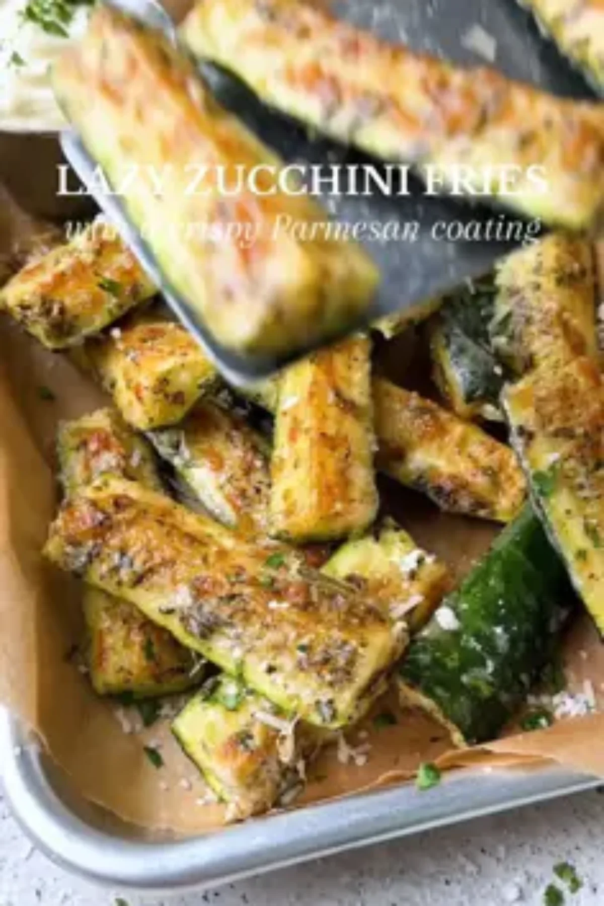 Crispy keto zucchini fries served with a small dish of dipping sauce on a light wood surface.
