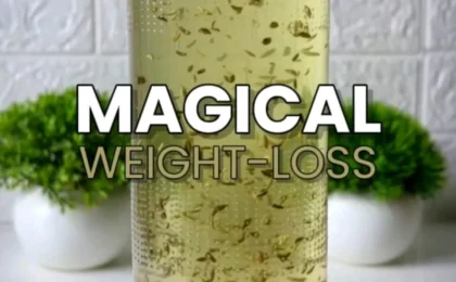 A glass of golden weight-loss drink with lemon slices, fresh mint, and ginger on a bright kitchen counter.