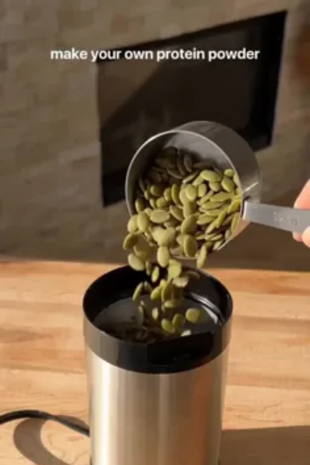 Assorted raw seeds and a glass jar of homemade seed protein powder on a wooden kitchen table