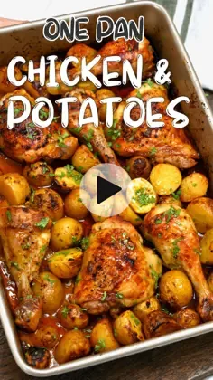 One pan chicken and potatoes in a metal sheet pan with drumsticks, thighs, and crispy yellow potatoes garnished with parsley.