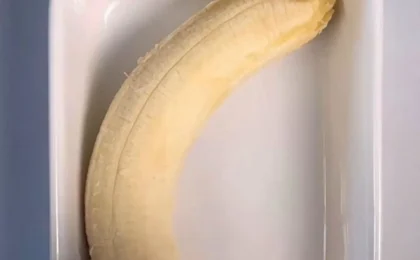 A stack of golden carrot and banana pancakes on a plate with a fork beside them.