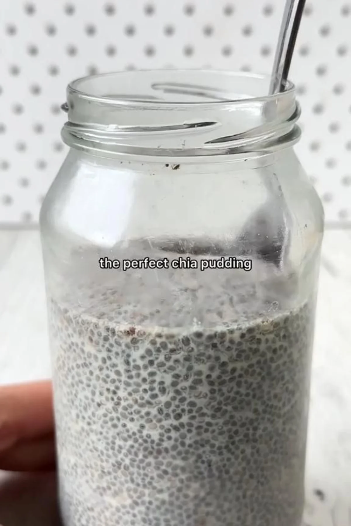 A glass jar of creamy vanilla chia pudding topped with fresh mixed berries and a sprinkle of granola.