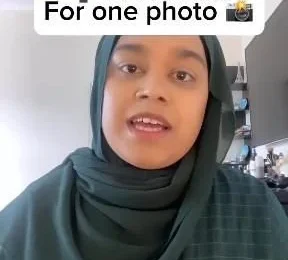 Woman in hijab holding a sign that reads $700 for one photo