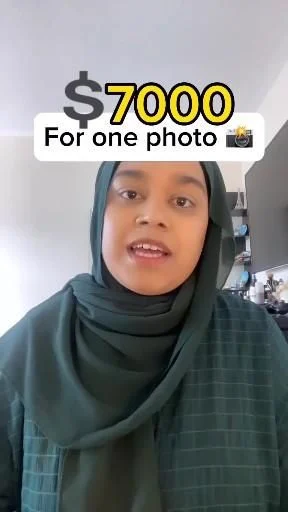 Woman in hijab holding a sign that reads $700 for one photo